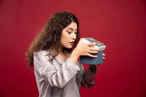Curly Jovem Mulher Verificando Caixa Presente Fundo Vermelho Foto Alta — Fotografia de Stock