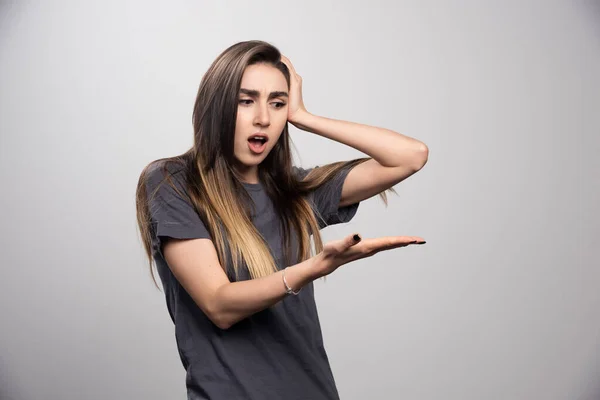 Förvånad Kvinna Tittar Hennes Hand Och Står Över Grå Bakgrund — Stockfoto