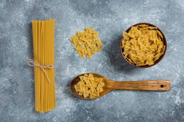 未煮熟的弓面通心粉和用木勺做的意大利面 高质量的照片 — 图库照片