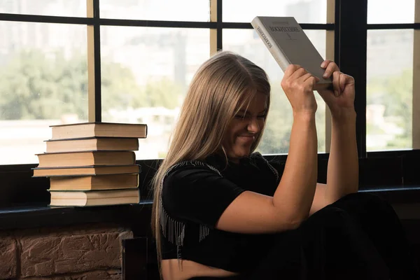 Pencerenin kenarına kitap fırlatan kızgın kadın. 