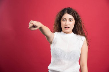 Kadın kırmızı arka planda kamerayı işaret ediyor. Yüksek kalite fotoğraf