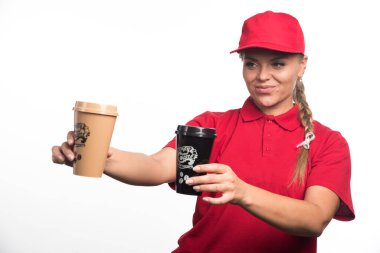 Kırmızı üniformalı kadın beyaz arka planda iki fincan kahve veriyor. 