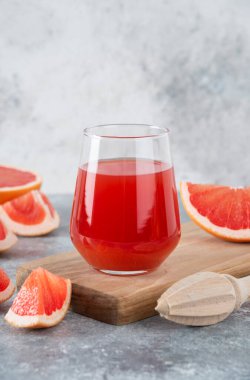 Bir bardak taze greyfurt suyu, yanında da meyve dilimleri ve ahşap kağıt. Yüksek kalite fotoğraf