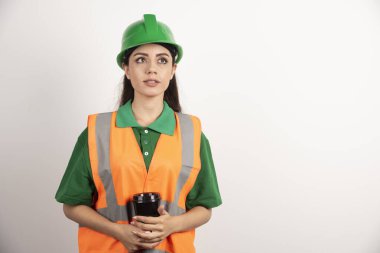 Siyah kupa tutan ve başka tarafa bakan genç bir inşaatçı kadın. Yüksek kalite fotoğraf