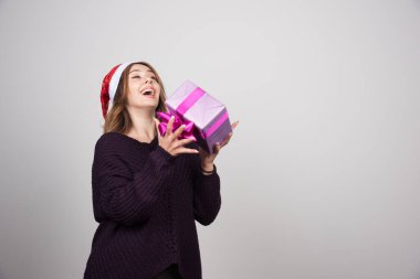 Noel Baba şapkalı genç bir kadın elinde bir hediye kutusu tutuyor. Yüksek kalite fotoğraf