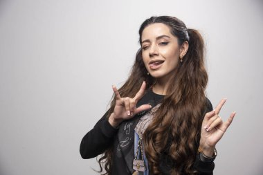 Gri arka planda birden fazla işaret veren genç bir kızın portresi. Yüksek kalite fotoğraf