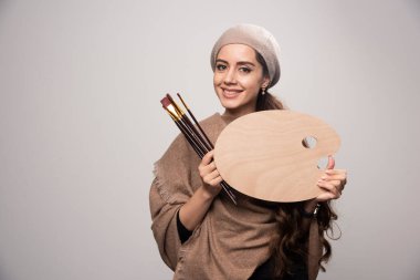 Bere takan sanatçı kız fırçasını ve ahşap paletini tutuyor ve olumlu hissediyor. Yüksek kalite fotoğraf