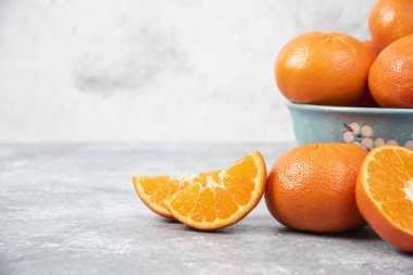 Tam ve sulu taze portakal meyvelerini taştan bir arka fona yerleştirilmiş bir kasede dilimleyin. Yüksek kalite fotoğraf