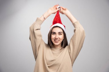 Gülümseyen kadın gri arka planda Noel Baba 'nın şapkasını tutuyor. Yüksek kalite fotoğraf