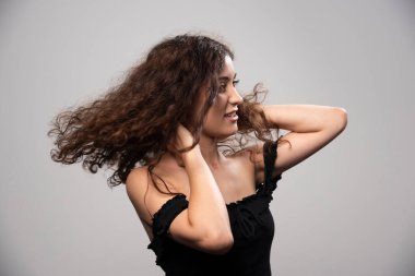 Siyah bluz giymiş kıvırcık saçlı genç bir kadın. Yüksek kalite fotoğraf