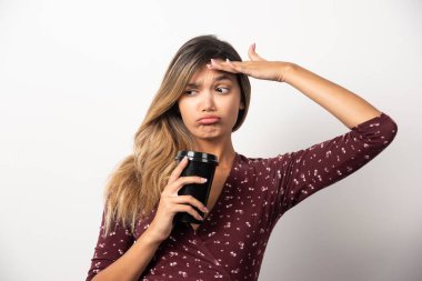 Beyaz arka planda bir bardak içki gösteren genç bir kadın. Yüksek kalite fotoğraf