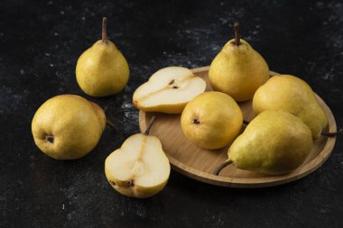Siyah yüzeyde ahşap bir tabak lezzetli sarı armut. Yüksek kalite fotoğraf