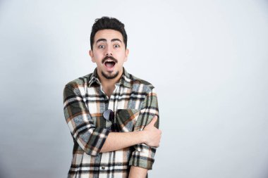 Beyaz duvarın üzerinde duran gözlüklü sakallı adamın portresi. Yüksek kalite fotoğraf