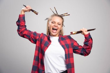 Sarışın sanatçı fırça tutuyor, onlara bakıyor ve eğleniyor. Yüksek kalite fotoğraf