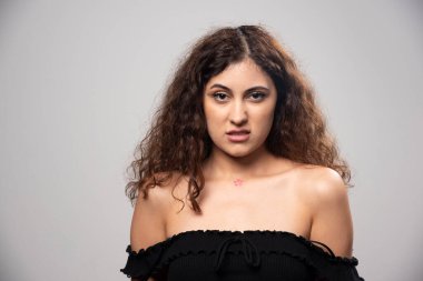 Siyah bluz giymiş kıvırcık saçlı genç bir kadın. Yüksek kalite fotoğraf