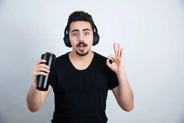 Morena Modelo Hombre Los Auriculares Sosteniendo Una Taza Mostrando Gesto —  Fotos de Stock