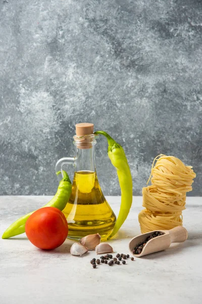 Rauwe Pasta Nesten Fles Olijfolie Peperkorrels Groenten Witte Tafel Hoge — Stockfoto