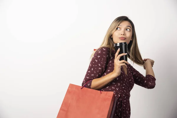 お店のバッグを持っている若い女性と白を背景に飲み物のカップ 高品質の写真 — ストック写真