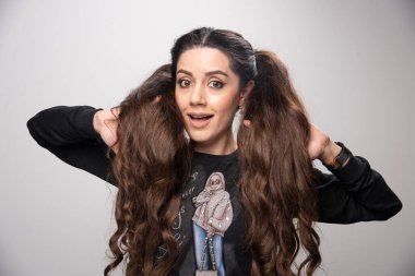 Parmak izi eşofmanlı genç bir kadın saçına hafifçe dokunuyor. Yüksek kalite fotoğraf