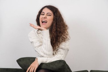 Koyu yeşil kanepesinde elinde yastıkla oturan genç bir kadın. Yüksek kalite fotoğraf