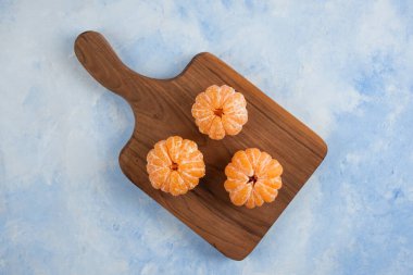 Ahşap kesme tahtasının üzerinde üç taze soyulmuş mandalina. Üst Manzara. Yüksek kalite fotoğraf