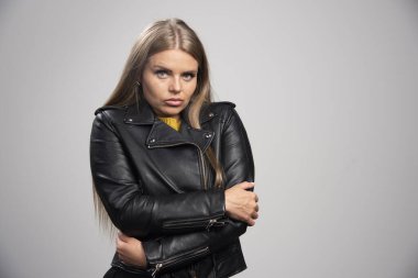 Siyah deri ceketli sarışın kız soğurken ceketini sıkıca tutuyor. Yüksek kalite fotoğraf