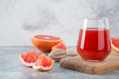 Bir bardak taze greyfurt suyu, yanında da meyve dilimleri ve ahşap kağıt. Yüksek kalite fotoğraf