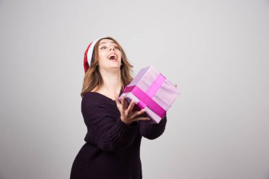 Noel Baba şapkalı genç bir kadın elinde bir hediye kutusu tutuyor. Yüksek kalite fotoğraf