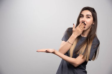 Şaşırmış bir kadın elini gösteriyor ve ağzını kapatıyor. Yüksek kalite fotoğraf