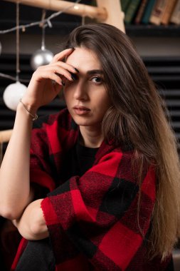 Kareli ekoseli genç bir kadın Noel balolarının yanında poz veriyor. Yüksek kalite fotoğraf