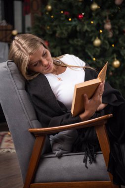 Siyah battaniyeli genç bir kadın oturmuş kitap okuyor. Yüksek kalite fotoğraf