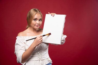 Sarışın sanatçı sanat eserlerini gösteriyor ve şüpheli görünüyor. Yüksek kalite fotoğraf