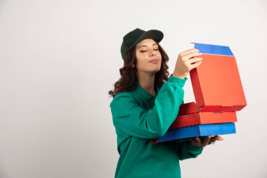 Yeşil üniformalı kadın kurye sıcak pizzayı kokluyor. Yüksek kalite fotoğraf