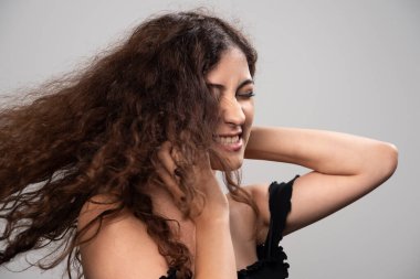 Siyah bluz giymiş kıvırcık saçlı genç bir kadın. Yüksek kalite fotoğraf