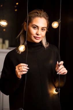 Siyah kazaklı, ayakta duran ve poz veren çekici bir kadının portresi. Yüksek kalite fotoğraf