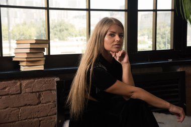 Pencerenin yanında kitaplarla poz veren genç bir kadın