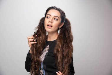 Saçlarını gri arka planda tutan genç ve güzel bir kadın. Yüksek kalite fotoğraf