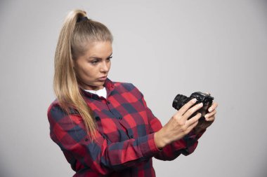 Kareli gömlekli sarışın manken fotoğraf çekerken profesyonel ve odaklanmış görünüyor. Yüksek kalite fotoğraf