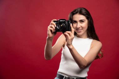 Kırmızı arka planda kamerayla fotoğraf çeken güzel bir kadın. Yüksek kalite fotoğraf