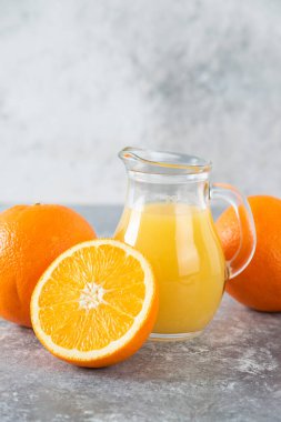 Taş zemin üzerinde taze portakal meyveleri olan cam bir sürahi meyve suyu. Yüksek kalite fotoğraf