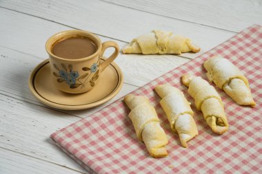 Beyaz ahşap zemin üzerinde kurabiyeler olan bir fincan çay.