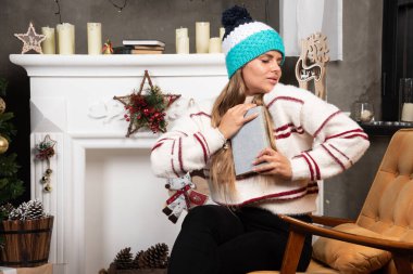 Sarışın kadın şöminenin yanında kitabı kucaklıyor. Yüksek kalite fotoğraf