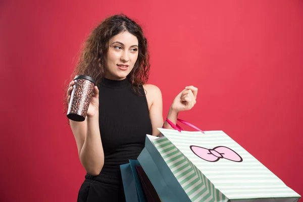 Vrouw Met Beker Tonen Haar Aankopen Rode Achtergrond — Stockfoto