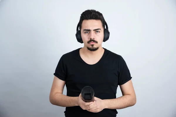 Modello Uomo Bruna Cuffia Con Una Tazza Contro Muro Bianco — Foto Stock