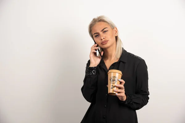 Kobieta Rozmawiająca Przez Telefon Komórkowy Trzymająca Filiżankę Kawy Wysokiej Jakości — Zdjęcie stockowe