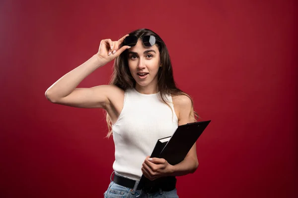 Joven Mujer Bonita Con Gafas Sosteniendo Cuadernos Sobre Fondo Rojo — Foto de Stock