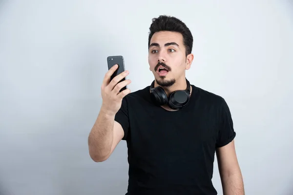 Brünetten Mann Modell Mit Kopfhörer Und Telefon Gegen Weiße Wand — Stockfoto