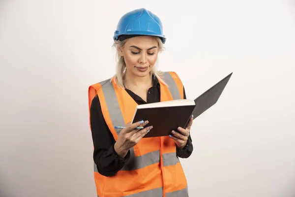 Schöne Bauarbeiterin Beim Prüfen Von Zetteln Auf Weißem Hintergrund Hochwertiges — Stockfoto