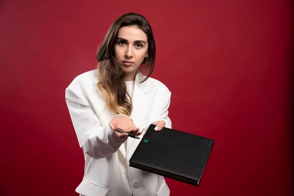 赤い背景にノートを提供するビジネス女性 高品質の写真 — ストック写真