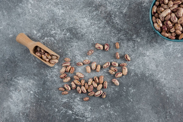 Bowl of dry beans and wooden spoon on marble background. High quality photo